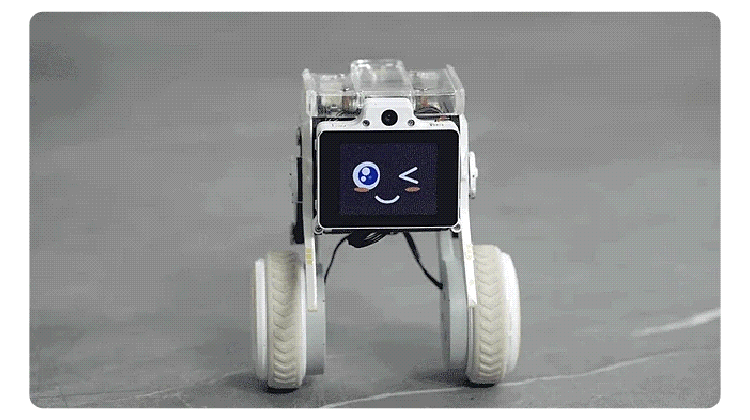 Small transparent robot on four white wheels, with a square screen showing a winking face.