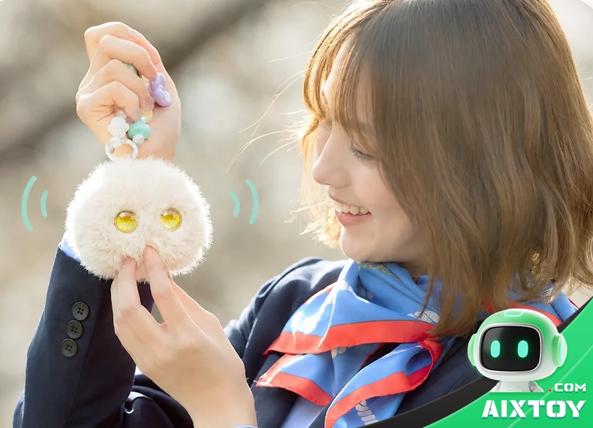 A girl holding up a Fuzozo AI plush pendant companion from Robopoet, showing its round fluffy body and large iridescent eyes