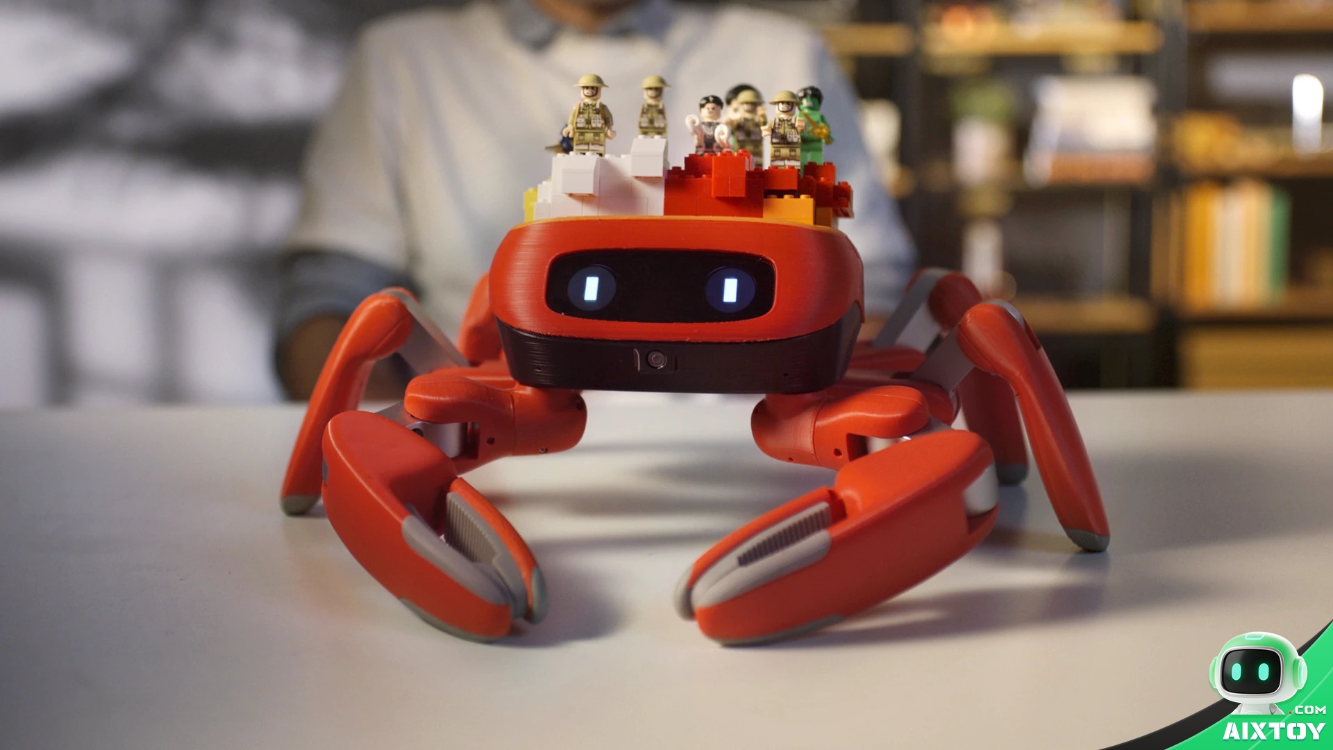 Jumper crab robot on a desk carrying toy minifigures on a small brick platform Jumper crab robot on a desk carrying toy minifigures on a small brick platform