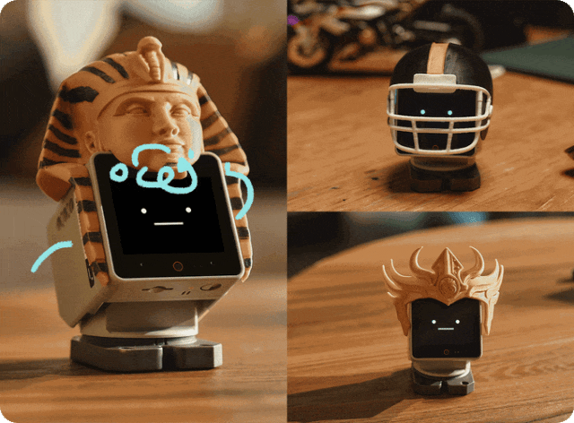 StackChan ESP32-S3 robot with community-made costumes including a headdress, helmet and crown